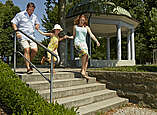 Eine Frau, ein Mann und ein Kind gehen eine Treppe hinab. Im Hintergrund der Pavillon im Uferpark.
