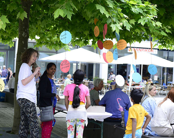 Erwachsene und Kinder beim Fest, im Hintergrund weiße Sonnenschirme