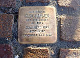 messingfarbene Platte eingelassen zwischen Pflastersteinen mit Erinnerungstext an Elsa Hammer: Hier wohnte Elsa Hammer geborene Fellheimer, Jahrgang 1884, deportiert 1943 Auschwitz, ermordet 24.0.1943