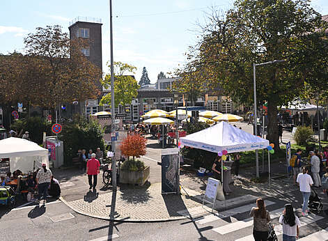 Blick auf eine Platz mit Sonnenschirmen und Menschen.