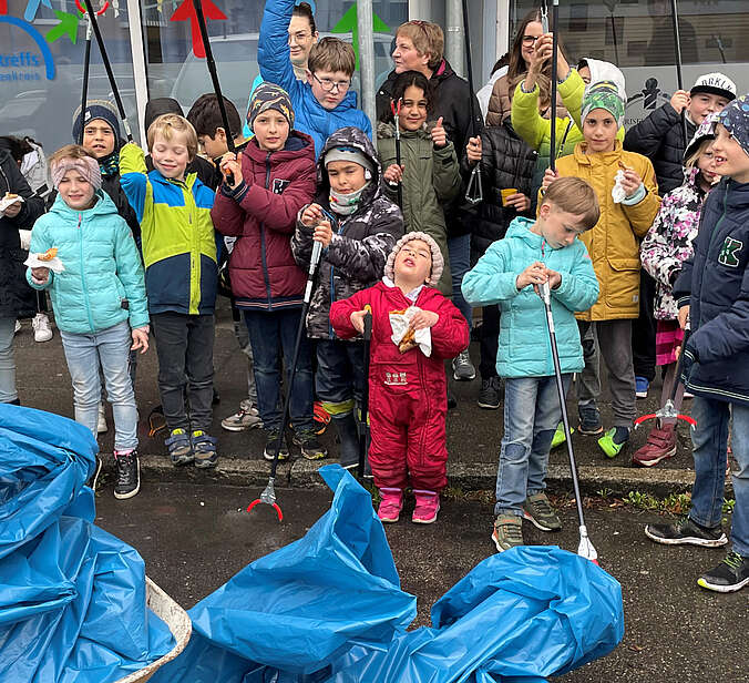 Blaue Müllsäcke, die von Kindern und Erwachsenen gefüllt wurden.