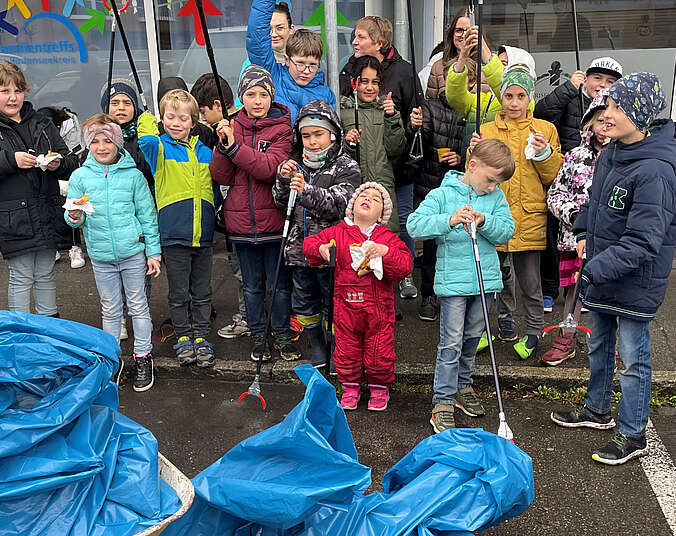 Blaue Müllsäcke, die von Kindern und Erwachsenen gefüllt wurden.