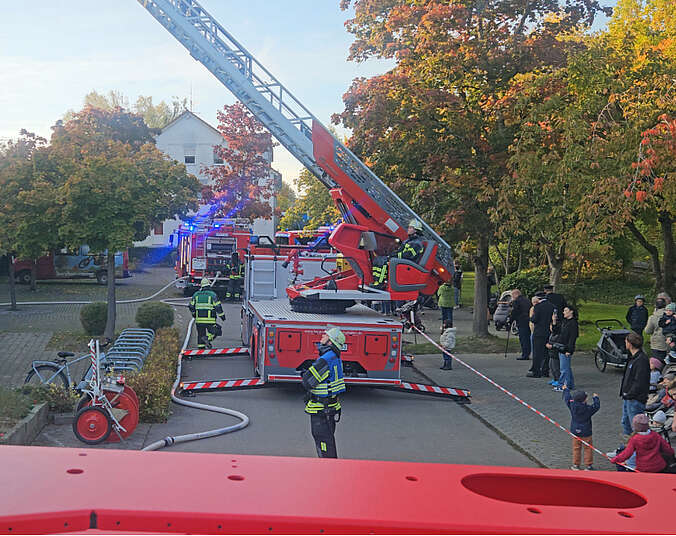 Feuerwehrauto mit ausgefahrener Drehleiter und Einsatzkräften