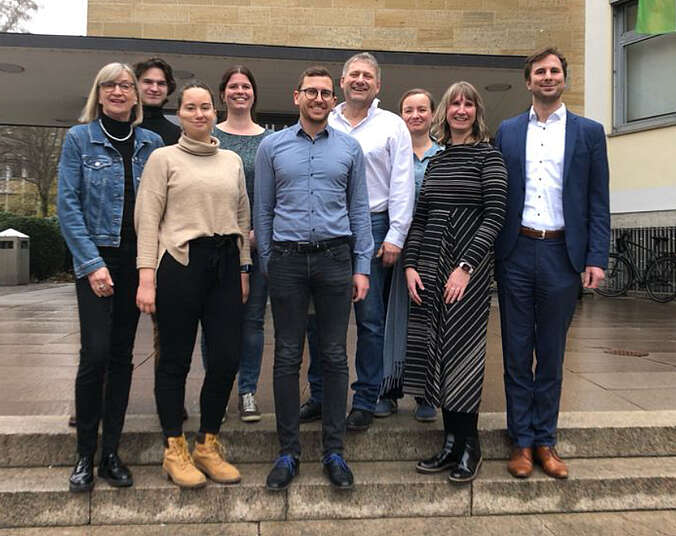 Männer und Frauen stehen auf der Treppe vor einem Gebäude.