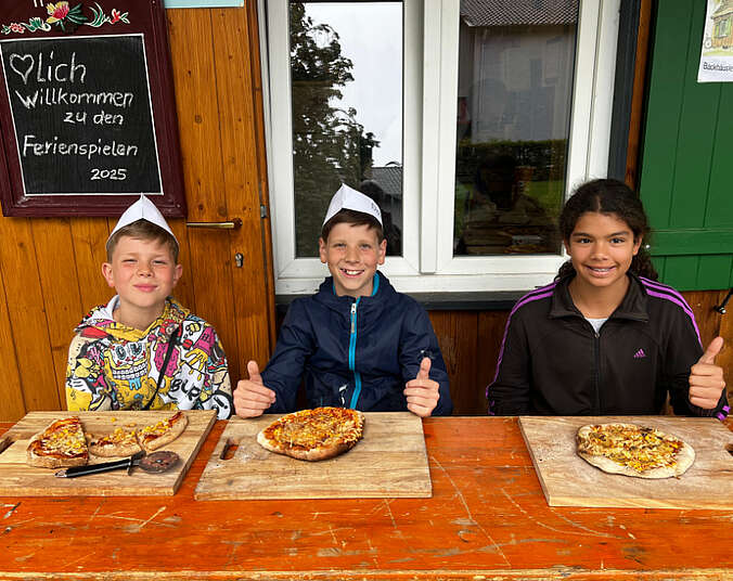 Drei Jungs sitzen am Tisch mit je einer Pizza