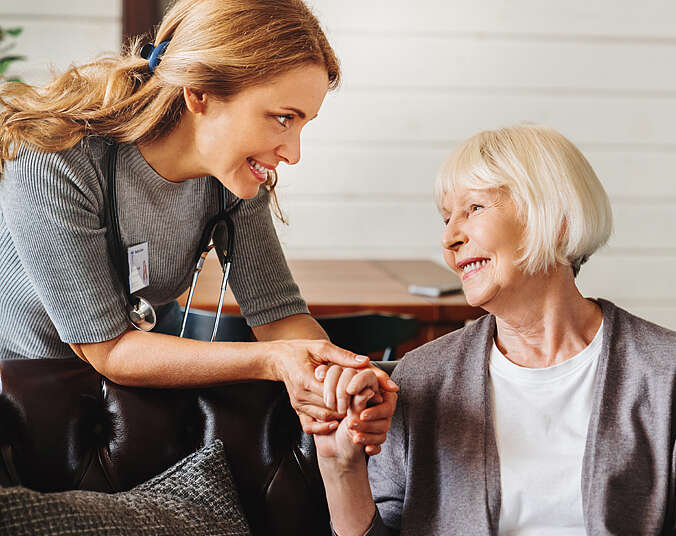 Eine Frau hält einer älteren Frau die Hand