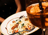 Teller mit Pasta und einem Cocktail auf einem Tisch.