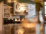 Zeppelinstube im Restaurant Lukullum mit übergroßen historischen Postkarten an der Wand. Im Vordergrund ein Bild von Graf Zeppelin mit einem fliegenden Zeppelin.