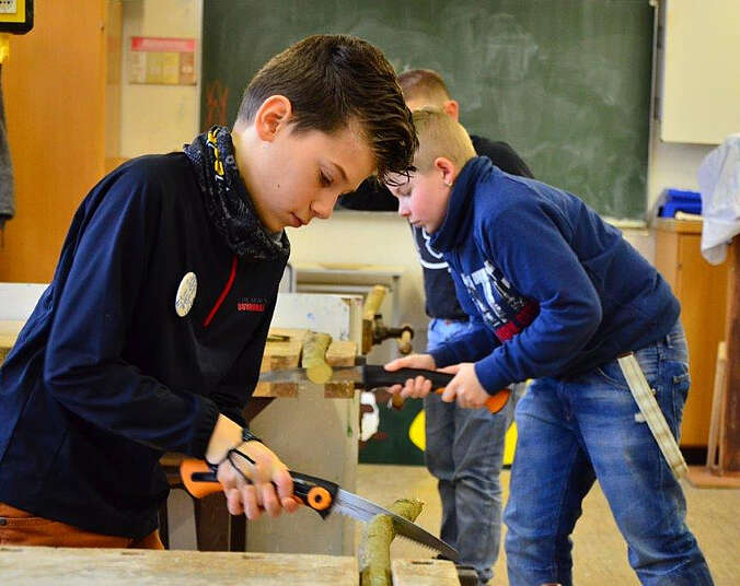 Drei Jungen arbeiten mit Handsägen.