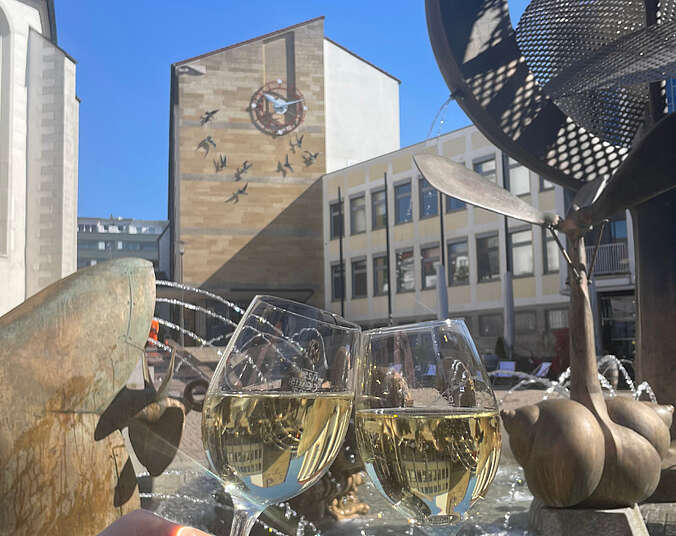 Weingläser vor dem Brunnen und dem Rathaus.