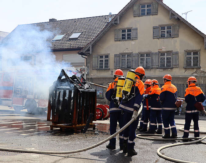 Jugendlichen in blau-orangen Anzügen mit einer Feuerwehrspritze löschen Gegenstand