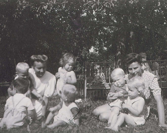 Eltern und Kinder sitzen auf einer Wiese