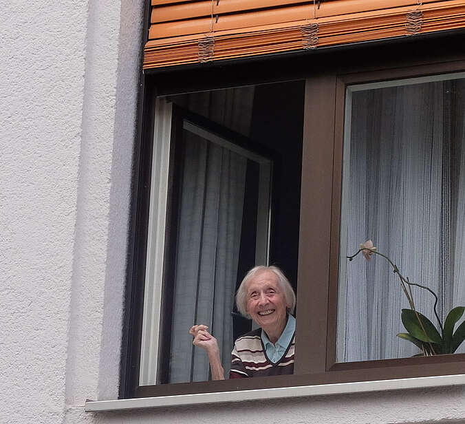 Seniorin steht am Fenster