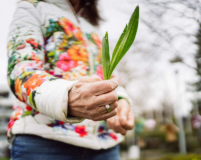 Eine Frau hält Kräuter in der Hand.