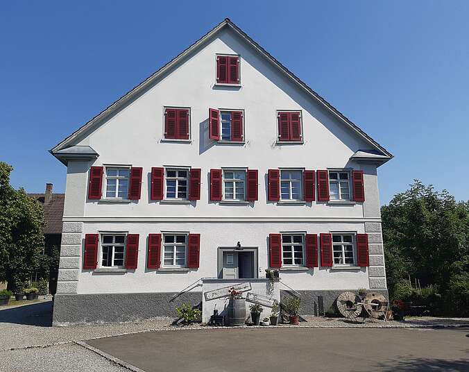 Alte renovierte Mühle in Ittenhausen mit einem Weinfass, Blumen, zwei Stülen und einem Tisch - vor der Treppe, die zum offenen Eingangstüre führt.