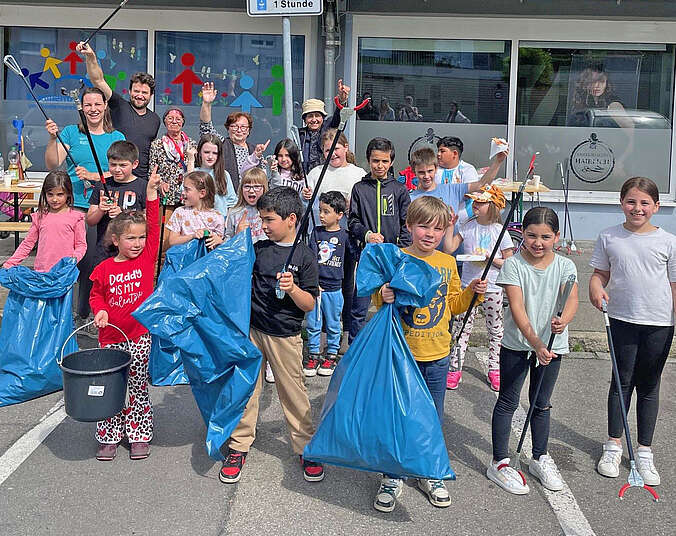 Kinder und Erwachsene mit blauen Müllbeuteln