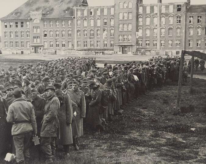 Historische Aufnahme mit einer Gruppe von Soldaten vor einer Häuserzeile