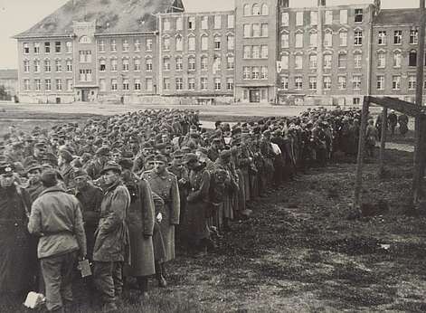 Historische Aufnahme mit einer Gruppe von Soldaten vor einer Häuserzeile