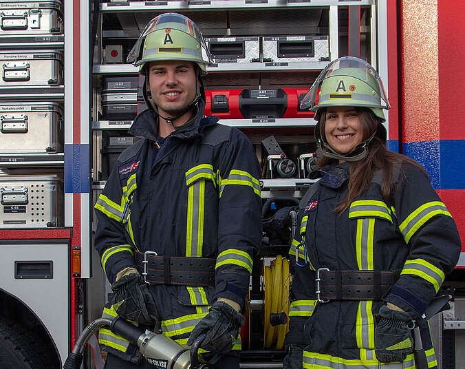 Feuerwehrfrau und Feuerwehrmann in Einsatzkleidung