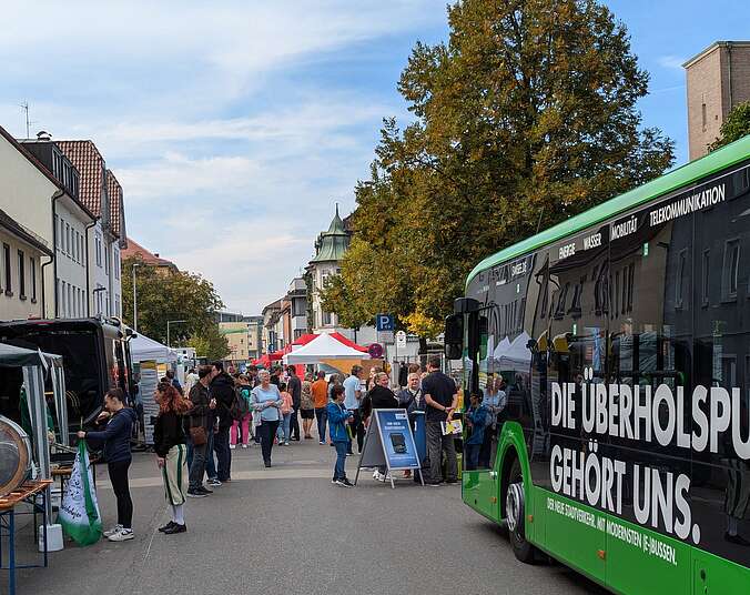 Menschen, Stände und parkender Bus auf Straße