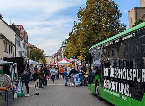 Menschen, Stände und parkender Bus auf Straße