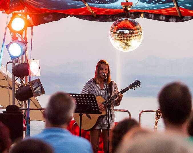 Frau auf Bühne mit Gitarre in der Hand