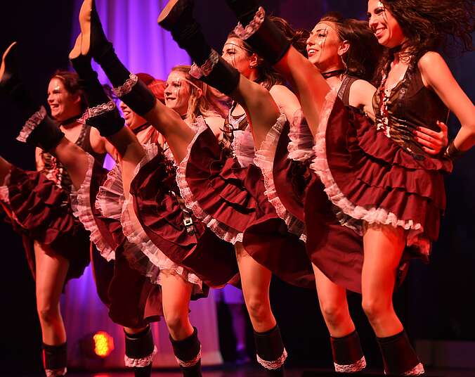 Frauen tanzen in Kostümen auf einer Bühne.