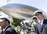 Festzug: Zeppelin-Modell begleitet von jungen Männern