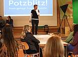 Friederike Lutz spricht mit Mikrofon vor Leinwand