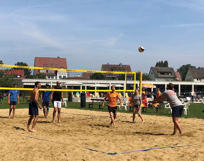 Frauen und Männer spielen eine Ball über ein Netz.