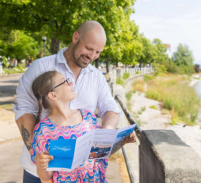 Vater und Tochter mit Flyer an Bodenseeufer