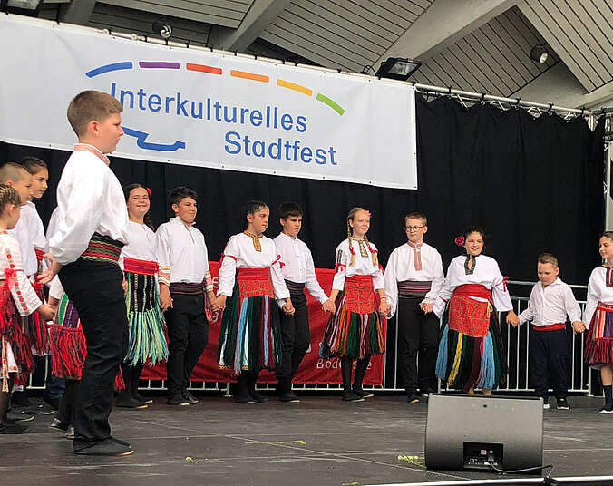 Kinder auf der Bühne mit weißen Hemden beim Tanzen.