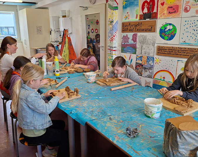 Kinder sitzen an einem Tisch und modellieren.