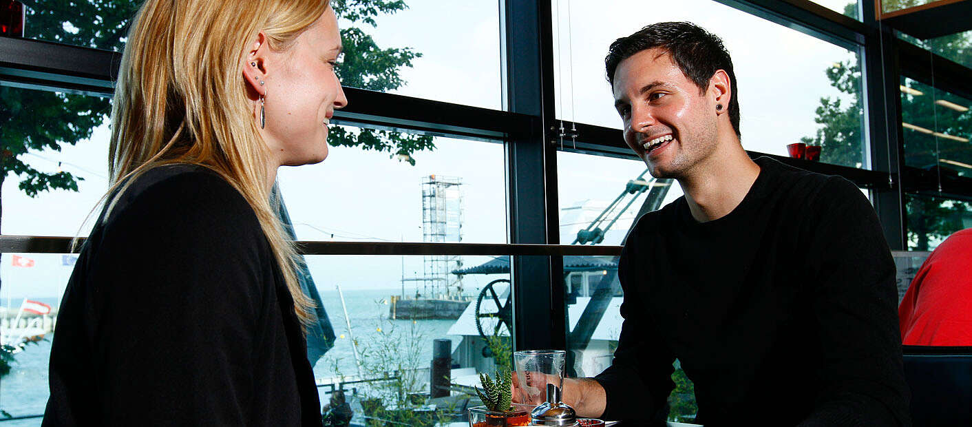 Mann und Frau sitzen im Cafe mit Seeblick zum Moleturm