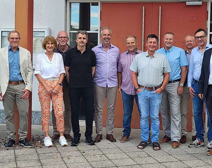 Männer und eine Frau stehen vor dem Rathaus Kluftern