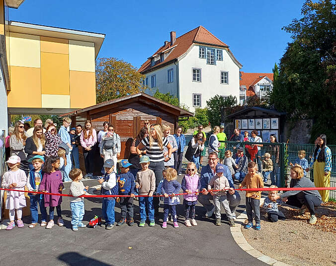 Kinder stehen hinter einem Band.