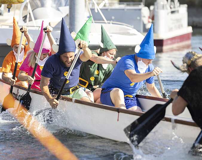 Verkleidete Menschen rudern gegeneinander im Drachenboot