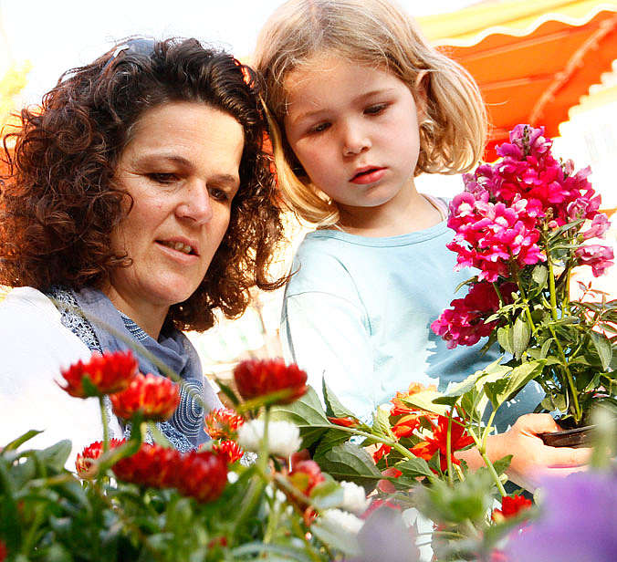 Mutter und Tochter schauen Blumen auf dem Markt an