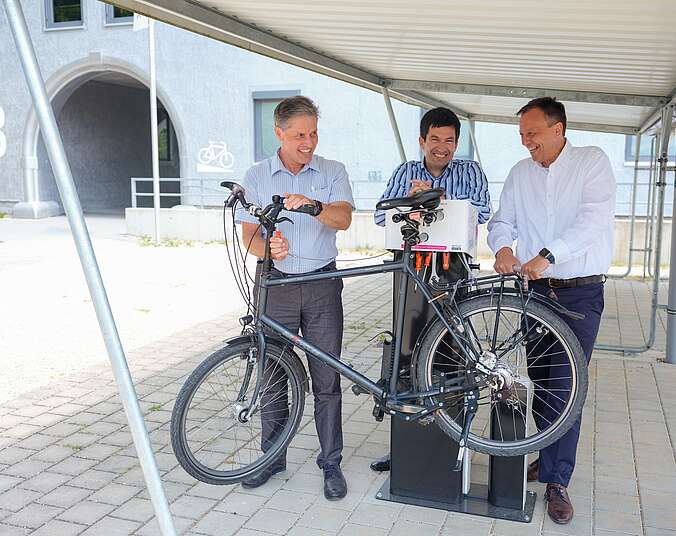 Drei Männer mit einem Fahrrad am RadService-Punkt.