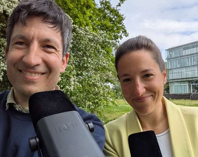 Mann und Frau mit Mikros schauen in die Kamera