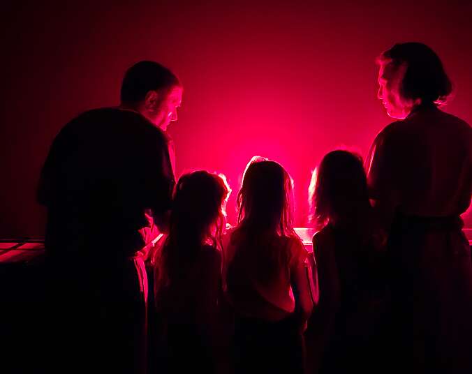 2 Erwachsene und 3 Kinder vor einer roten Lichtquelle