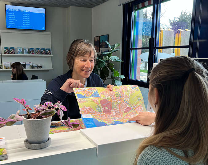 Frau lässt sich in der Tourist-Information beraten und den Stadtplan zeigen