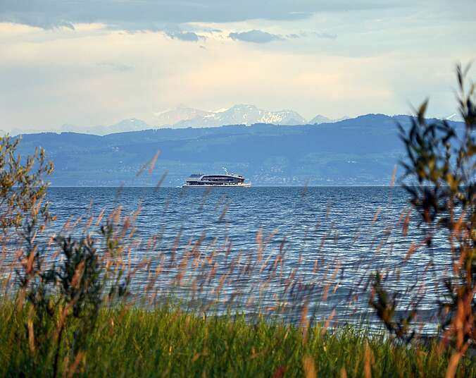 Blick auf den Bodensee - Schiff und die Berge im Hintergrund.