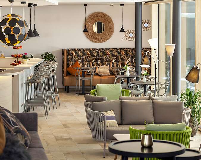 Moderne Loungemöbel in grau und grün im Vordergrund, links im HInergrund die moderne Bar im Hotel Knoblauch.
