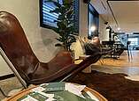 Moderner Stuhl und Tisch, im Hintergrund modern eingerichteter Raum mit Tischen und Stühlen.