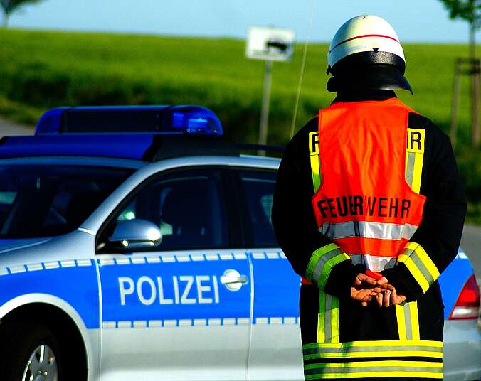 Ein Feuerwehrmann steht vor einem Polizeiauto