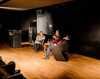 Menschen auf Bühne sprechen vor Publikum