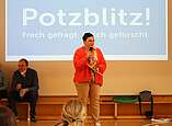 Frau spricht mit Mikrofon vor Leinwand