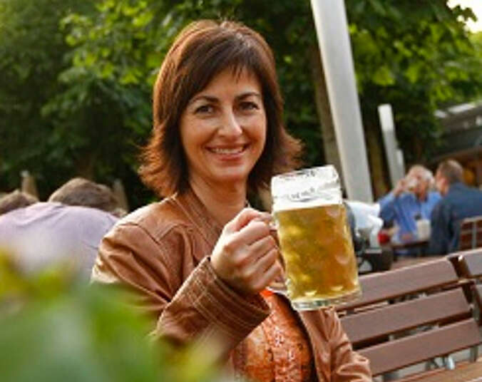 Frau mit einem Bier sitzt auf einer Bank.