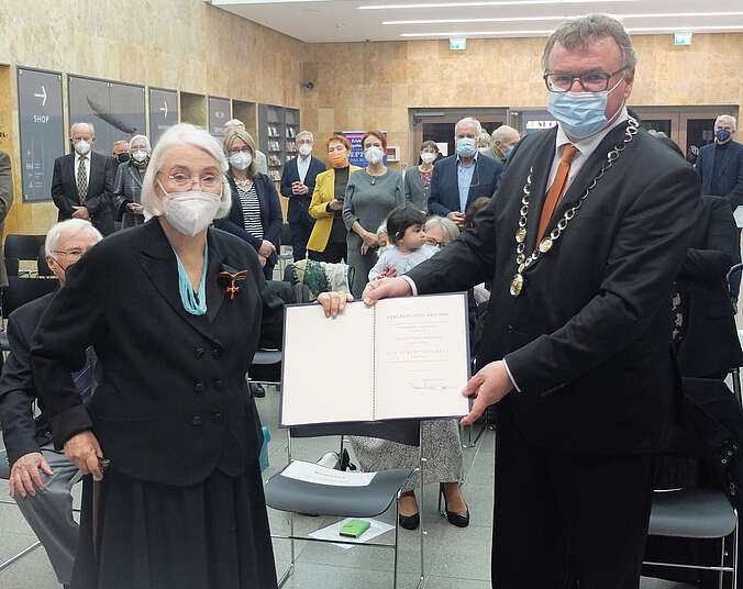 Eine Frau und ein Mann halten eine Urkunde in Händen.